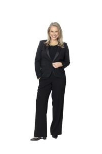 A personal brand photoshoot that captures a full length portrait of a lady in a black suit on a white background