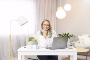 A personal brand photoshoot that captures a portrait  of a lady wearing a white shirt and sitting at her desk. 