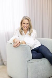 A personal brand photoshoot that captures a portrait of a lady wearing a white shirt and jeans sitting in a comfy lounge chair