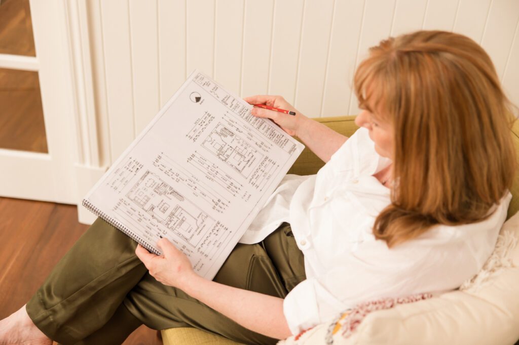 A lady sitting in a yellow arm chair looking at design plans