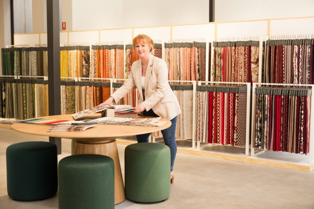 Personal Branding Photo of a female Interior designer standing looking at a rack of furnishing fabric swatches