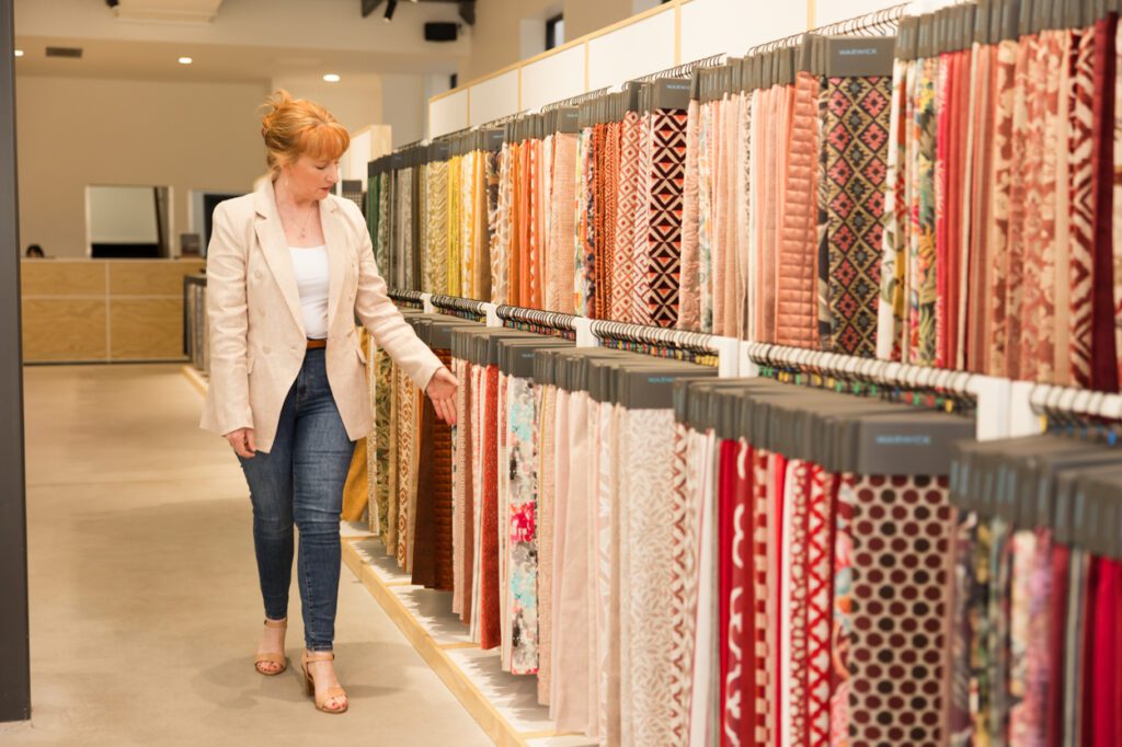 Personal Branding Photo of a female Interior designer standing looking at a rack of furnishing fabric swatches