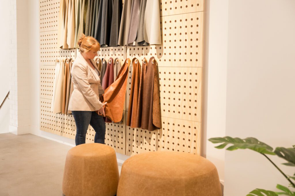 Personal Branding Photo of a female Interior designer looking at a wall with leather sample swatches hanging on it