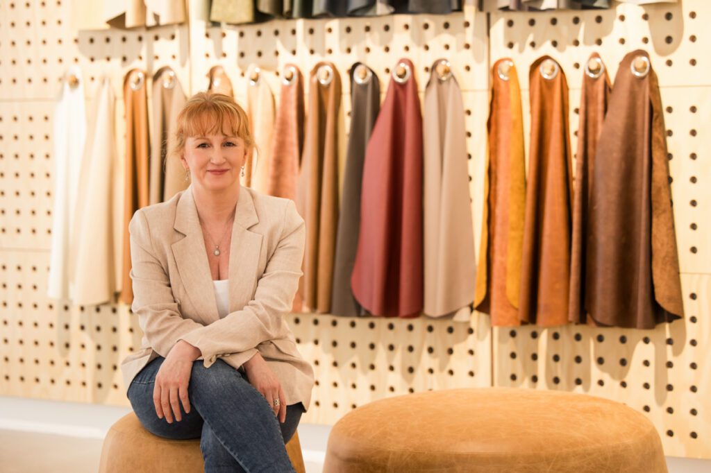 Personal Branding Photo of a female Interior designer sitting on a leather ottoman with leather sample swatches in the background