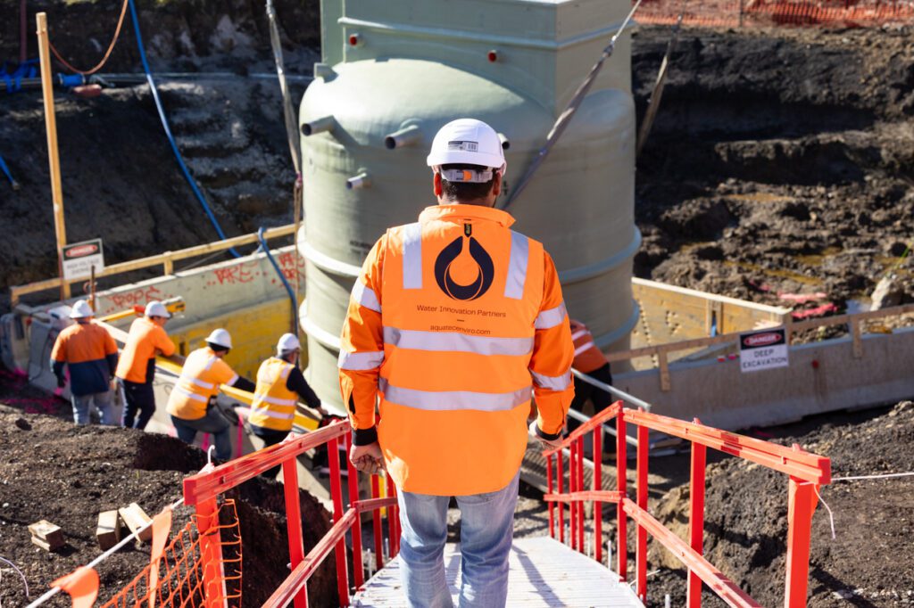 A male wearing high vis clothing and a hard hat walking down stairs towards a worksite