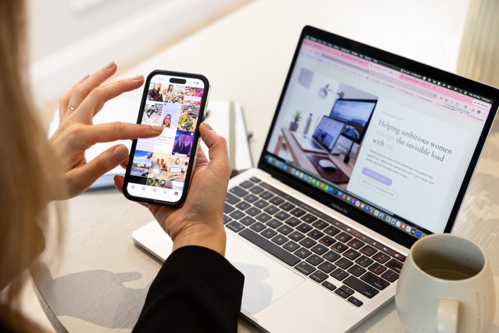 an image showing someone's fingers scrolling through their instagram grid with a laptop in the background